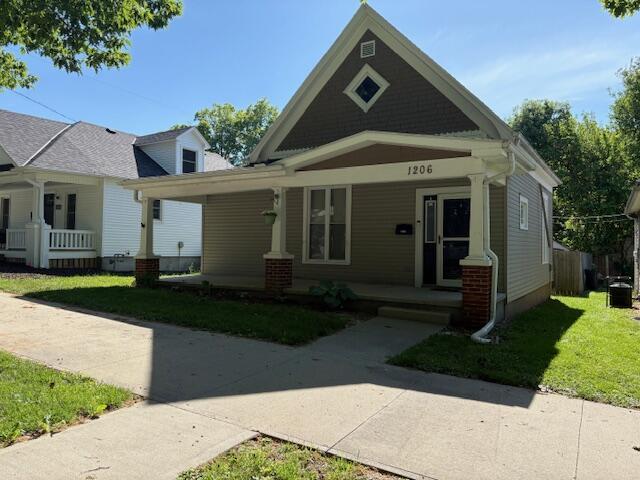 view of front of property featuring covered porch and a front lawn