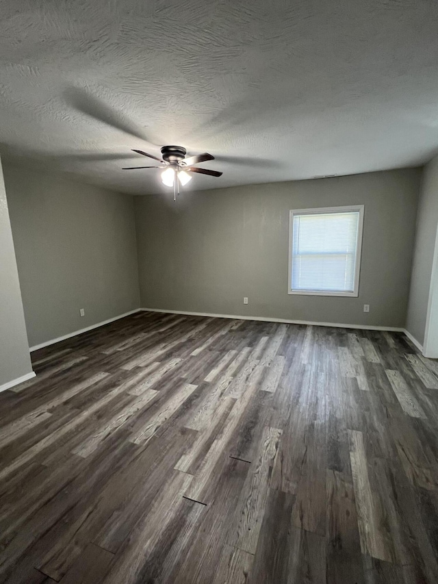 empty room featuring dark wood finished floors, a ceiling fan, and baseboards