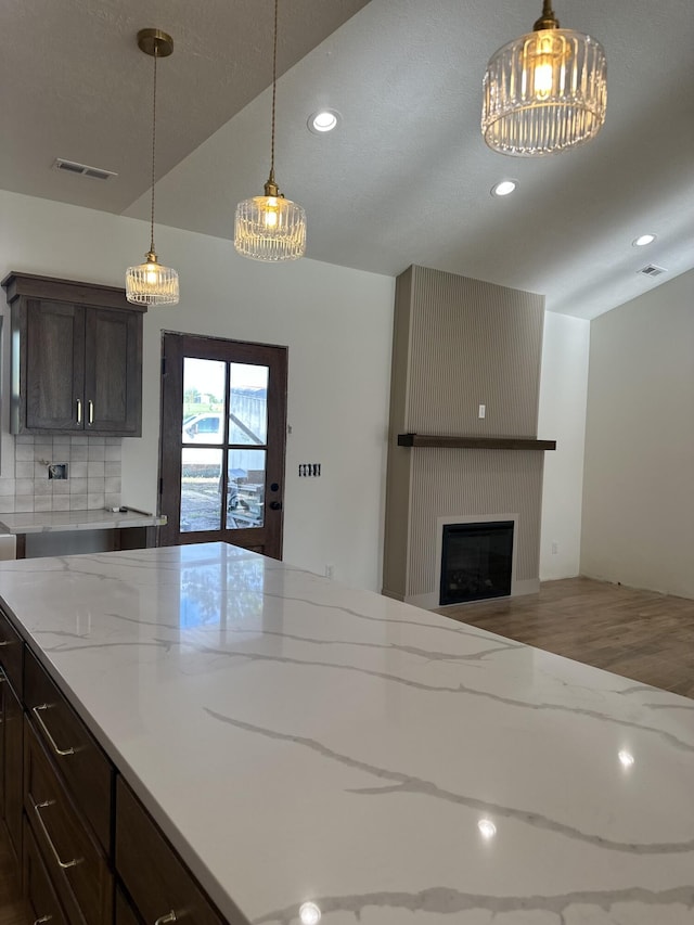 kitchen featuring recessed lighting, light stone counters, hanging light fixtures, a fireplace, and wood finished floors
