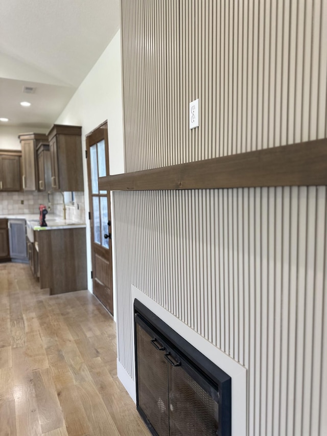 kitchen featuring light countertops, light wood-type flooring, lofted ceiling, tasteful backsplash, and dark brown cabinetry