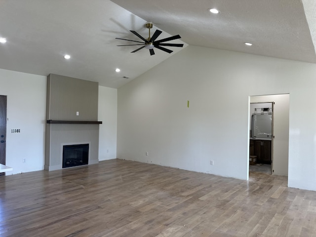 unfurnished living room with ceiling fan, wood finished floors, a fireplace, recessed lighting, and high vaulted ceiling