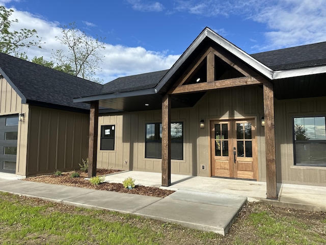 entrance to property with board and batten siding, a porch, and roof with shingles