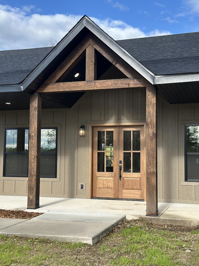 entrance to property with board and batten siding, roof with shingles, and french doors