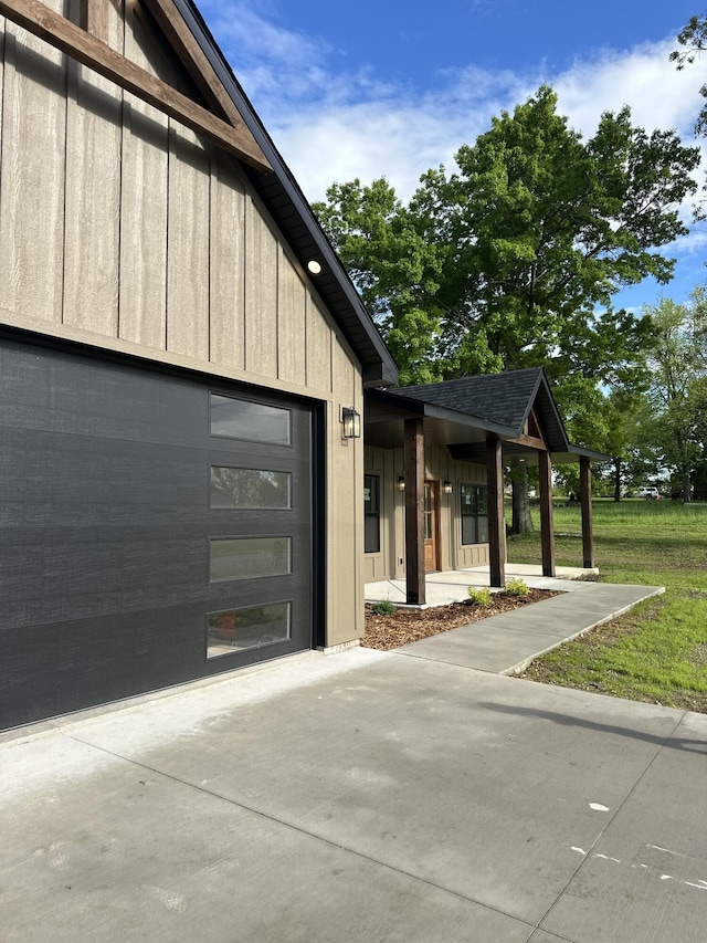 view of side of home featuring driveway, board and batten siding, and an attached garage