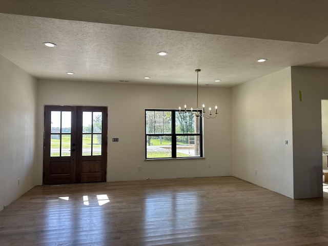foyer entrance with a textured ceiling, wood finished floors, a chandelier, recessed lighting, and french doors