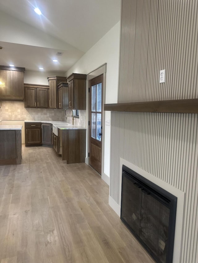 1988 Morris Rd, Mountain Grove, MO 65711 - kitchen featuring lofted ceiling, decorative backsplash, a glass covered fireplace, light countertops, and light wood-style flooring