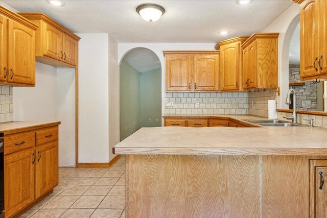 580 Cedar Hill Ln, Marshfield, MO 65706 - kitchen featuring a sink, arched walkways, backsplash, light countertops, and a peninsula