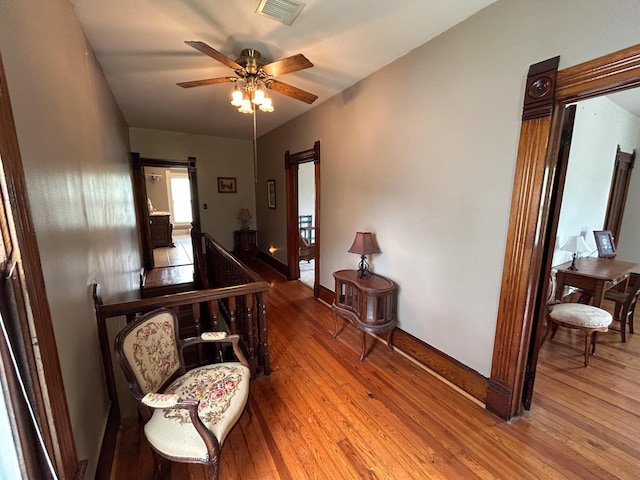 hall with wood finished floors, an upstairs landing, and baseboards