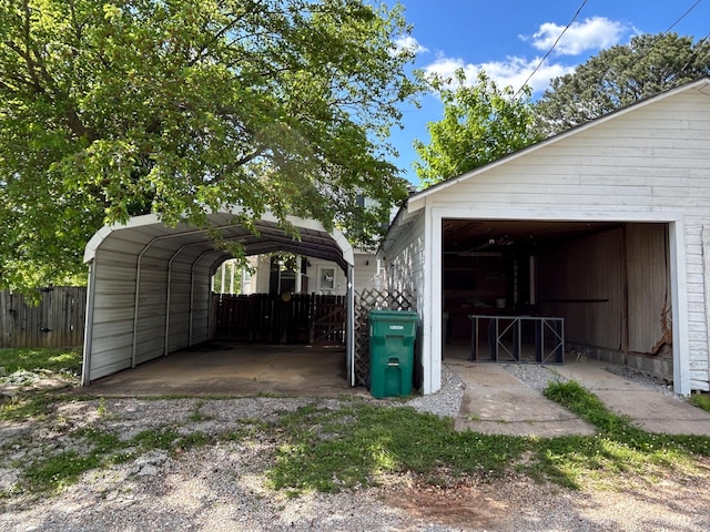 garage featuring fence and a carport