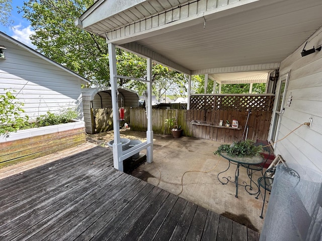deck with a storage unit, an outdoor structure, and fence