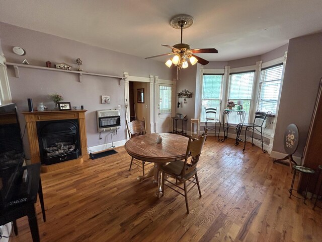 dining space featuring heating unit, wood finished floors, a ceiling fan, baseboards, and healthy amount of natural light