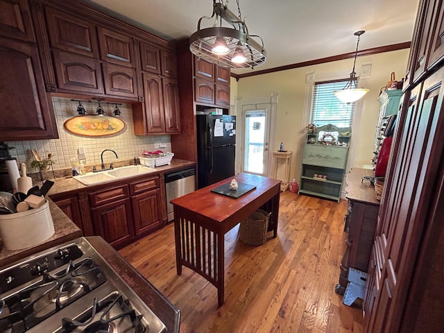 kitchen featuring stainless steel appliances, a sink, decorative backsplash, light wood-style floors, and ornamental molding