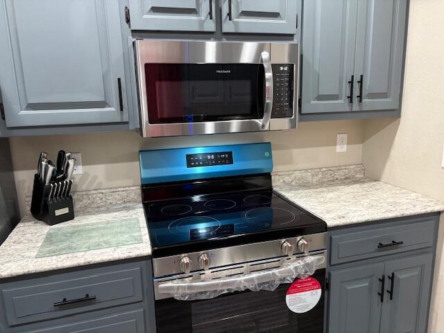 kitchen with appliances with stainless steel finishes, gray cabinetry, and light countertops