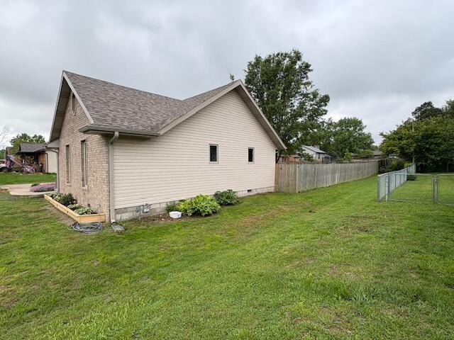 view of side of home with a shingled roof, crawl space, and brick siding