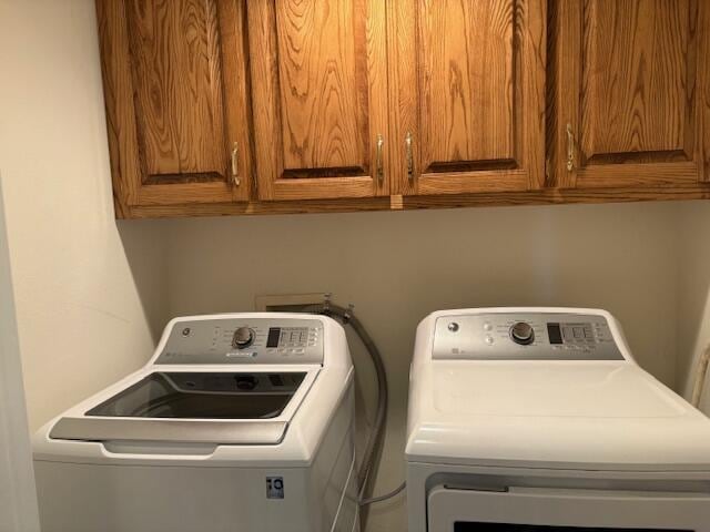 clothes washing area featuring washing machine and dryer and cabinet space