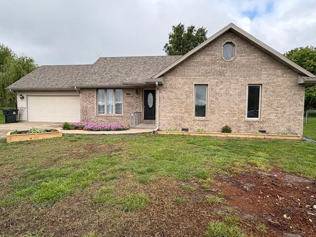 ranch-style home with brick siding, an attached garage, a front yard, and driveway