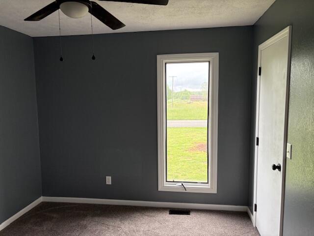carpeted empty room with plenty of natural light, ceiling fan, and baseboards