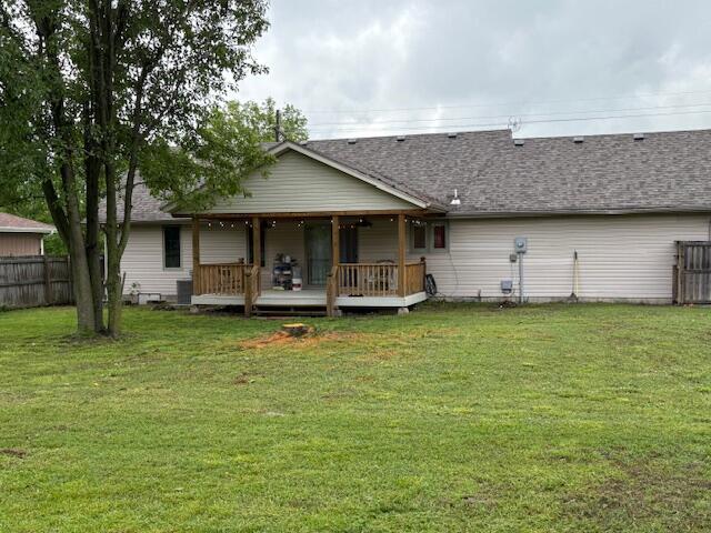 rear view of property with a deck and roof with shingles