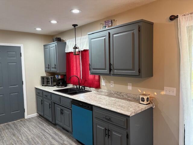 kitchen featuring dishwasher, a sink, gray cabinetry, light wood finished floors, and light countertops