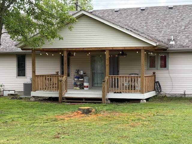 rear view of house featuring roof with shingles, a lawn, cooling unit, and a porch