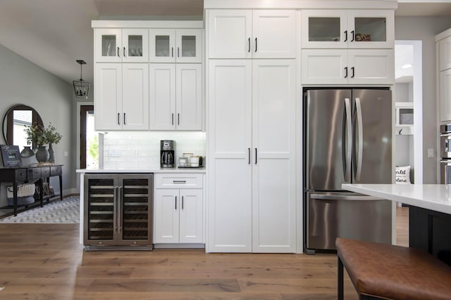 kitchen featuring stainless steel appliances, wine cooler, wood finished floors, light countertops, and white cabinetry