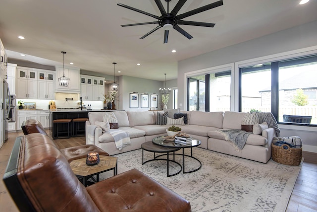 living area featuring light wood-style flooring, recessed lighting, ceiling fan, and a chandelier