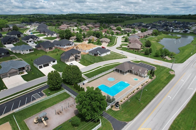 view of property location featuring a large body of water, a pool, and nearby suburban area