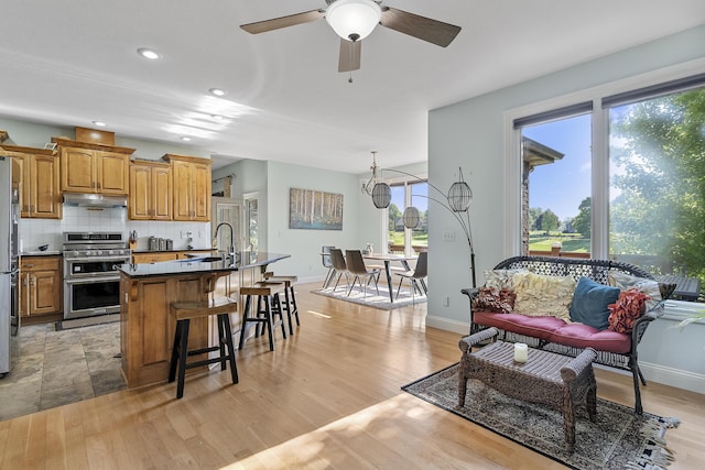 5998 S Parkhaven Ln, Springfield, MO 65810 - kitchen featuring appliances with stainless steel finishes, under cabinet range hood, a ceiling fan, a kitchen bar, and a center island with sink