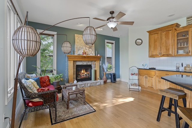 5998 S Parkhaven Ln, Springfield, MO 65810 - living room featuring a ceiling fan, a glass covered fireplace, light wood finished floors, and baseboards