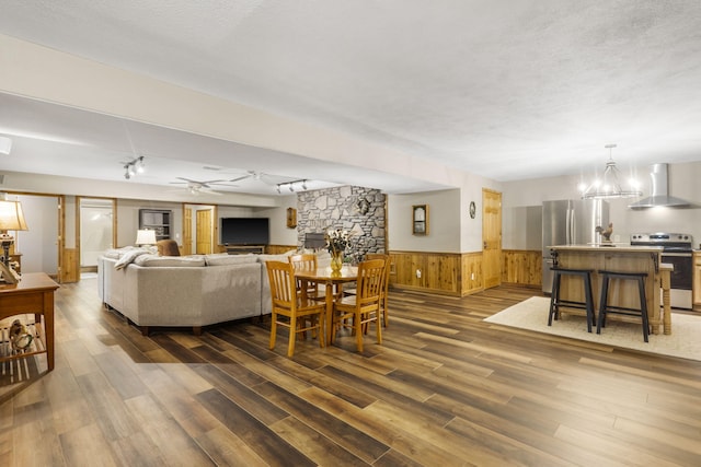 1294 Acacia Club Rd, Hollister, MO 65672 - living room featuring dark wood-style floors, a wainscoted wall, wood walls, rail lighting, and a chandelier