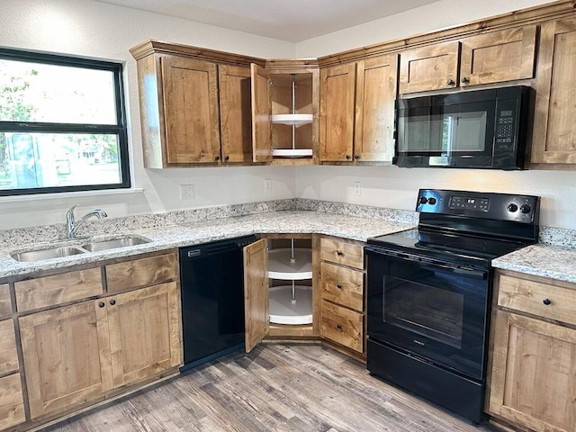 1712 S Jackson St, El Dorado Springs, MO 64744 - kitchen with black appliances, a sink, light wood-type flooring, light stone countertops, and brown cabinetry