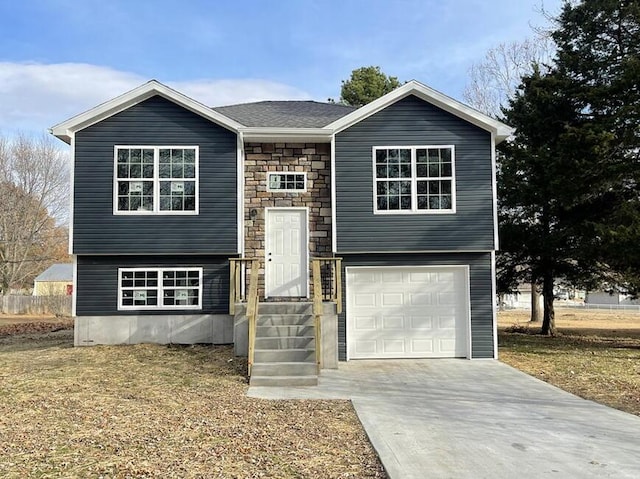 1712 S Jackson St, El Dorado Springs, MO 64744 - split foyer home with stone siding, an attached garage, driveway, and a front yard