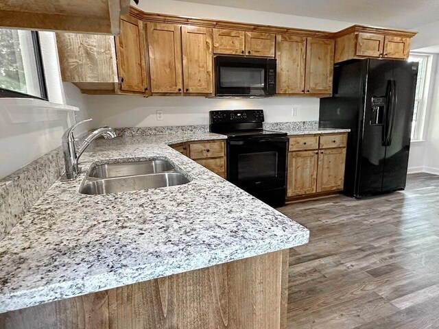 1712 S Jackson St, El Dorado Springs, MO 64744 - kitchen featuring black appliances, a sink, wood finished floors, brown cabinets, and light stone countertops