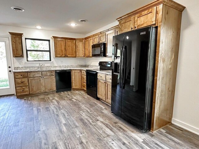 1712 S Jackson St, El Dorado Springs, MO 64744 - kitchen featuring black appliances, light wood-style floors, a sink, brown cabinets, and baseboards