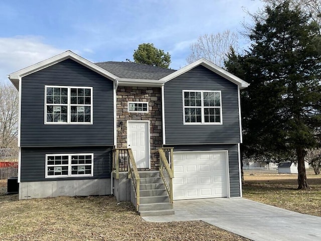 1712 S Jackson St, El Dorado Springs, MO 64744 - raised ranch featuring stone siding, an attached garage, and driveway