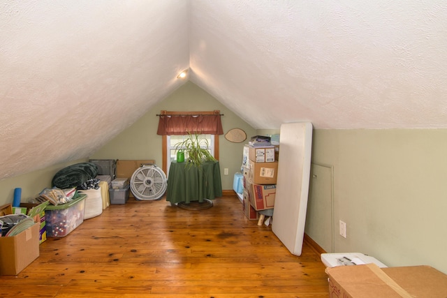 bonus room featuring a textured ceiling, wood-type flooring, and lofted ceiling