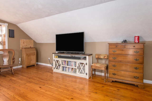 living area with lofted ceiling, wood-type flooring, and baseboards