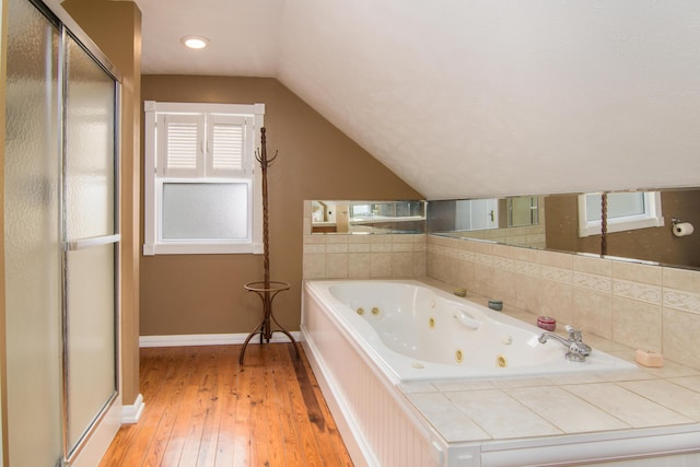 bathroom featuring lofted ceiling, hardwood / wood-style flooring, baseboards, a whirlpool tub, and a shower stall