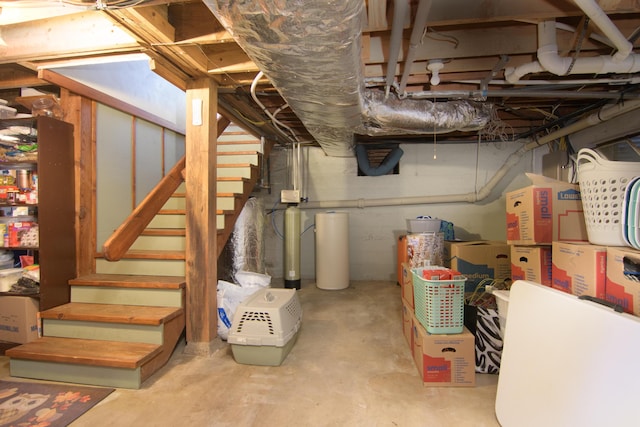 unfinished basement with stairway and a water softener