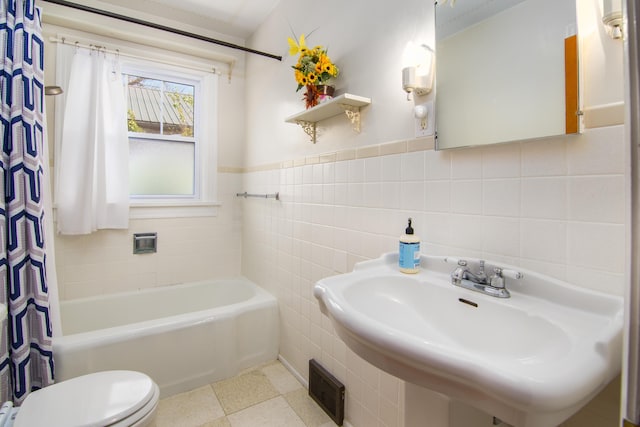 full bathroom featuring tile walls, toilet, a sink, and wainscoting