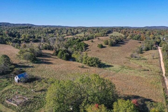 aerial view of property and surrounding area with a heavily wooded area and rural landscape