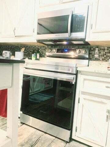 kitchen view of stainless steel appliances, white cabinets, and decorative backsplash