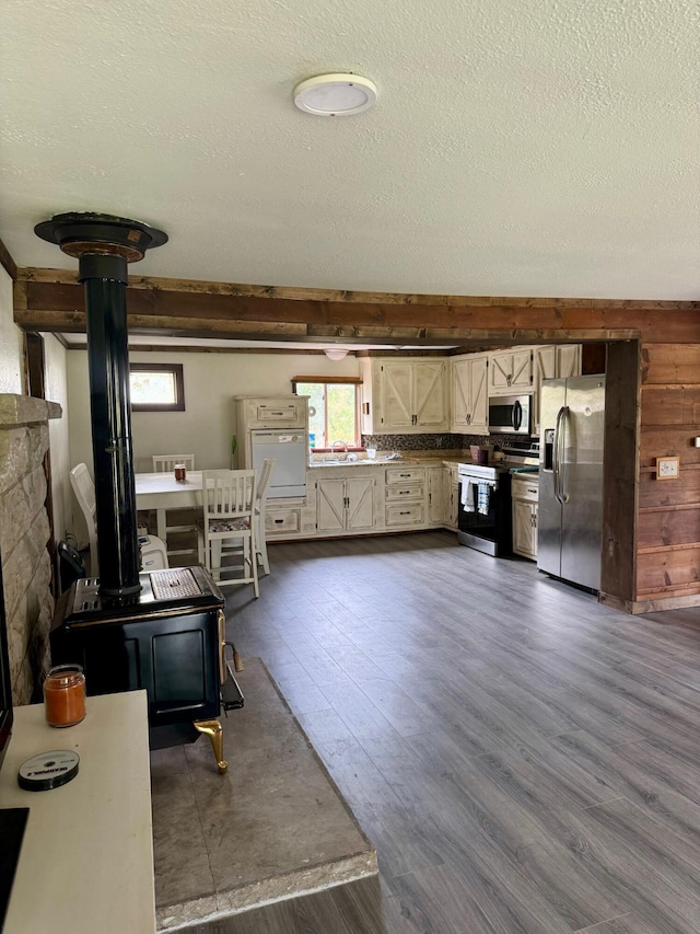 kitchen with stainless steel appliances, a textured ceiling, a sink, dark wood-type flooring, and a wood stove