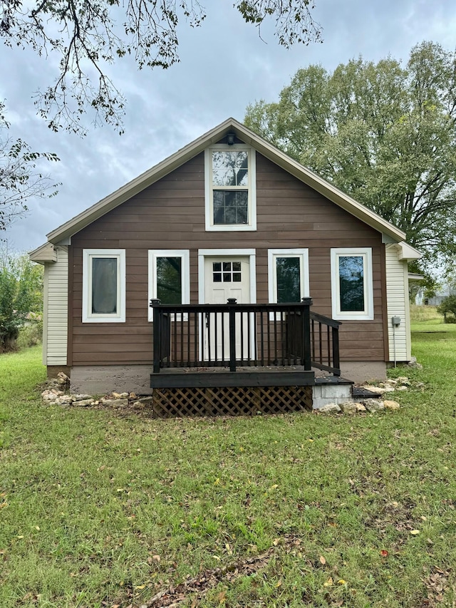 rear view of house with a wooden deck and a lawn