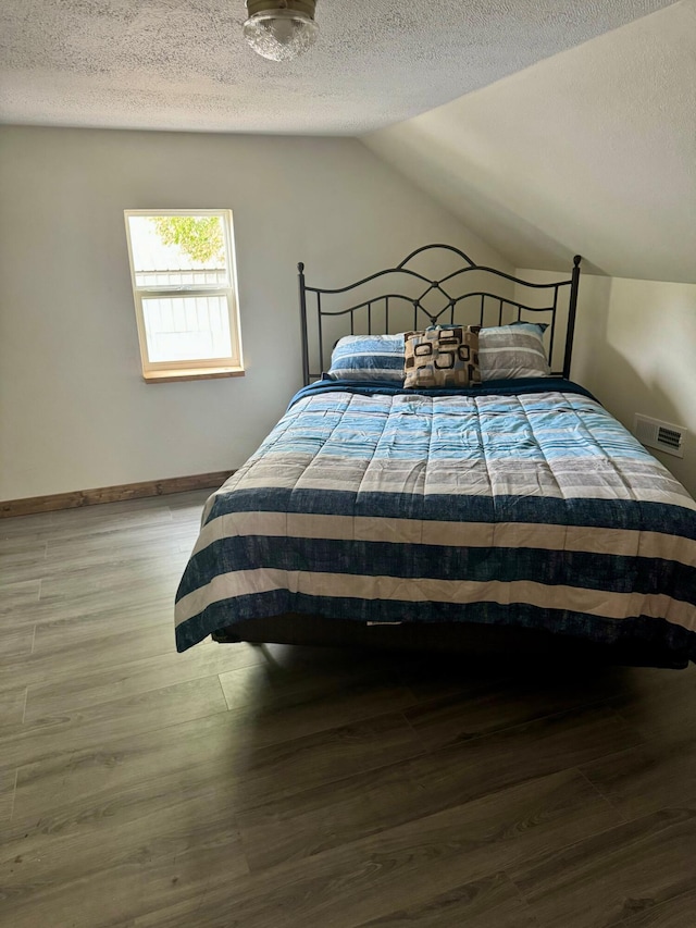bedroom with wood finished floors, vaulted ceiling, a textured ceiling, and baseboards