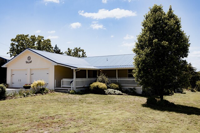 21246 County Road 295, Hermitage, MO 65668 - view of front facade featuring a front lawn, metal roof, covered porch, and an attached garage