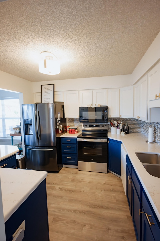 21246 County Road 295, Hermitage, MO 65668 - kitchen with appliances with stainless steel finishes, blue cabinetry, a sink, white cabinetry, and a textured ceiling