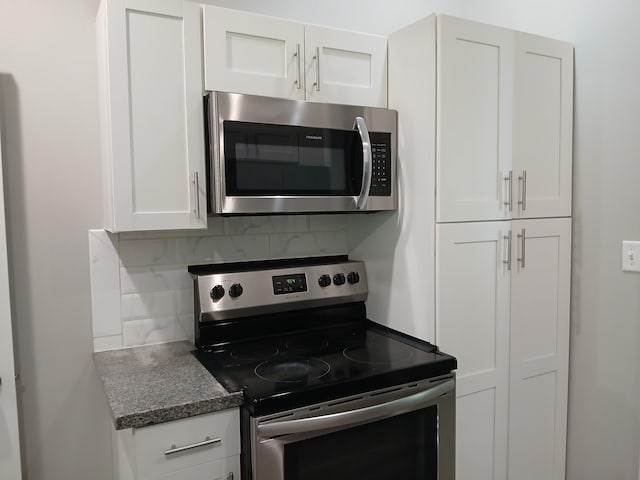 639 W Webster St, Springfield, MO 65802 - kitchen featuring appliances with stainless steel finishes, backsplash, white cabinets, and dark stone counters