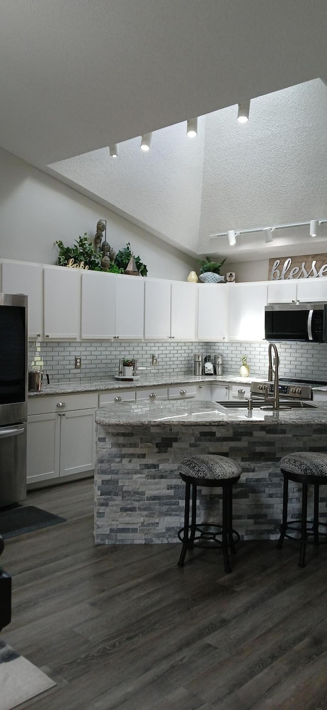 95 Starboard Dr, Kimberling City, MO 65686 - kitchen with appliances with stainless steel finishes, decorative backsplash, white cabinetry, dark wood-style floors, and light stone counters