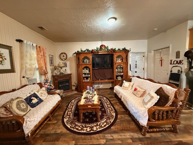 living area with dark wood-type flooring, a fireplace, and a textured ceiling